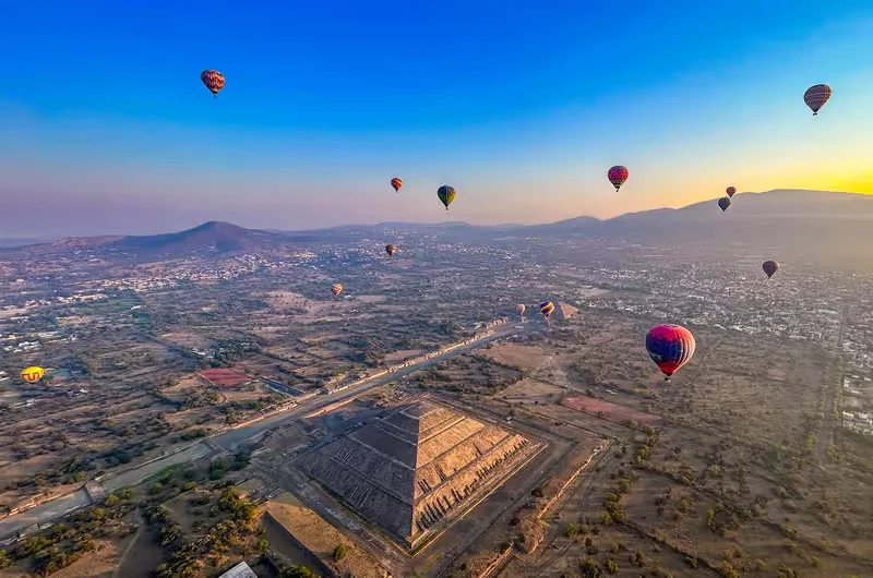 Hot air balloons floating over the Pyramid of the Sun at sunrise on a Teotihuacan pyramids balloon tour